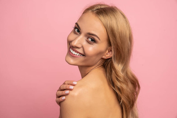 Beautiful sensual topless woman with long blonde hair posing isolated over pink background. Beauty concept. - Foto, afbeelding
