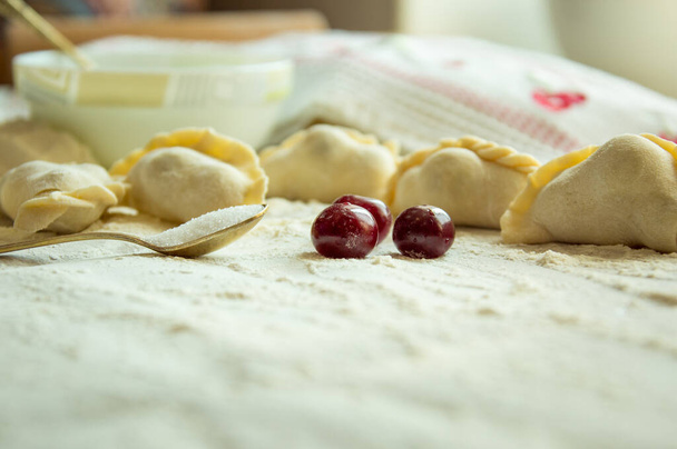 Het traditionele gerecht van de Oekraïense keuken is knoedels met kersen. Verse kersen en suiker worden in tortilla 's van vers deeg gedaan en gekookt. Dumplings met kersen zijn verslaafd aan koken. - Foto, afbeelding