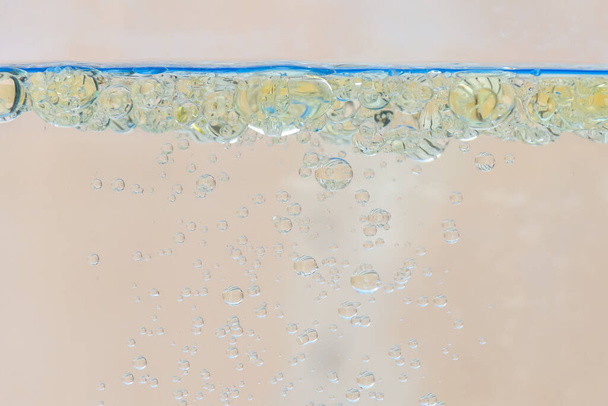 Oil bubbles in water with beige background. - Photo, Image