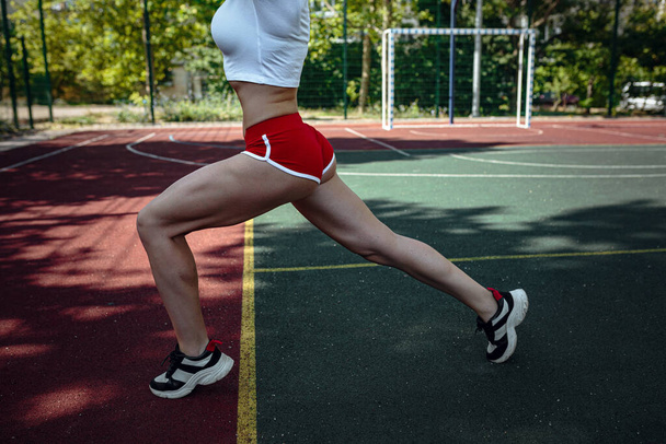 Joven mujer deportiva haciendo ejercicios al aire libre deportes, estilo urbano. Estilo de vida activo. concepto de bienestar de entrenamiento
. - Foto, imagen