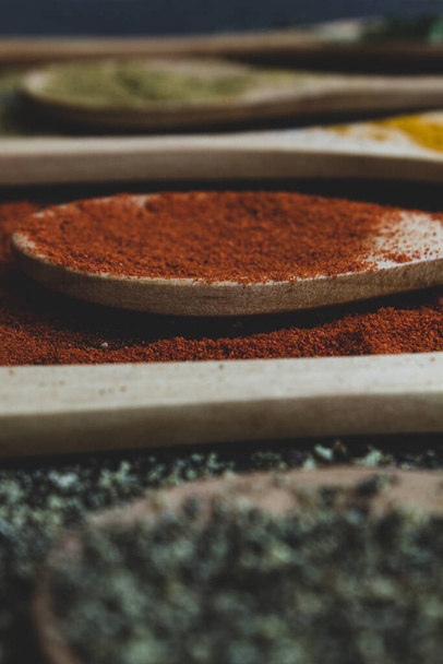 spice background on wooden spoons. Seasoning texture. Hibiscus, black pepper, paprika, cumin, curry, parsley - Photo, Image