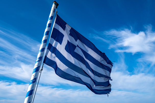 Görögország jel szimbólum. Görög zászló lobogott a zászlórúdon a szélben. Kék ég fehér felhőkkel, napos tavaszi nap - Fotó, kép