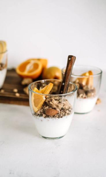 Muesli and natural yogurt with slices of fruits and nuts in a glass cup, healthy breakfast. - Foto, imagen