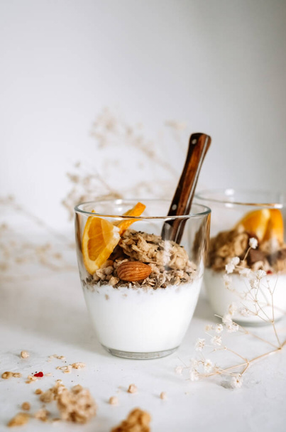 Natural yogurt and granola with slices of fruits and nuts in a glass cup, healthy breakfast.. High quality photo - Fotoğraf, Görsel
