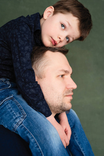 boy sits on father neck and hugs with his hands - Foto, immagini