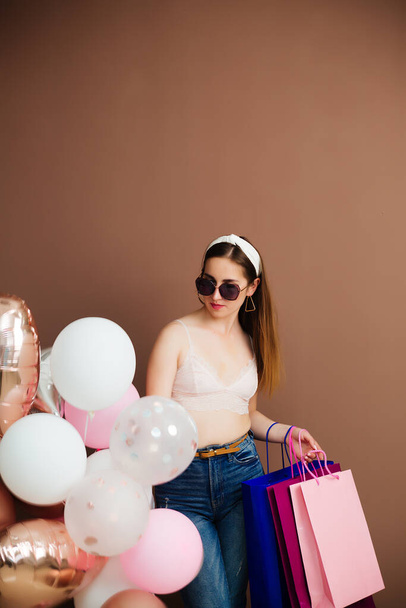 свята та концепція моди - щаслива молода жінка або дівчина-підліток з гелієвими кульками та покупками
 - Фото, зображення