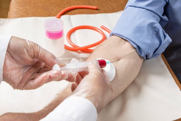 As mãos de uma enfermeira tomam o sangue de uma mão masculina da análise
 - Foto, Imagem