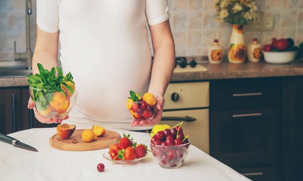 Eine schwangere Frau isst Obst. Selektiver Fokus. Lebensmittel. - Foto, Bild