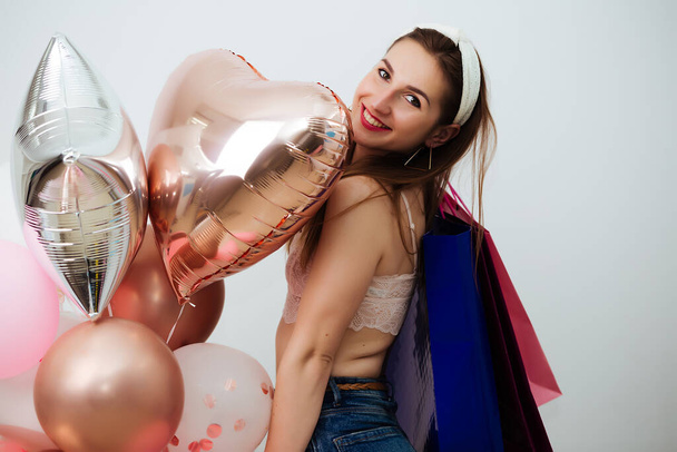 Portrait of pretty woman covering body with colorful balloons and packages - Fotografie, Obrázek