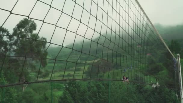 Régi szakadt röplabda háló egy sportpályán egy festői zöld parkban, egy gyönyörű erdős domb hátterében - Felvétel, videó