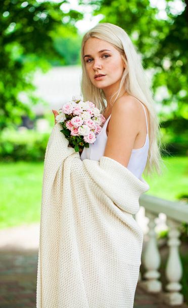 Closeup portrait of a young blonde girl with a bouquet of pink flowers in summer park - Φωτογραφία, εικόνα