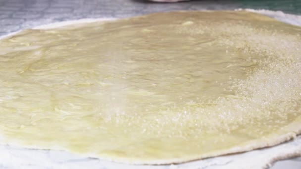 Öntözni a cukor-homok hengerelt ki a süteményt a kenyér tekercsek elkészítéséhez. Szelektív fókusz. - Felvétel, videó