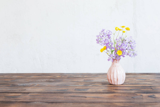 flowers in vase on wooden table on background white wall - Фото, изображение