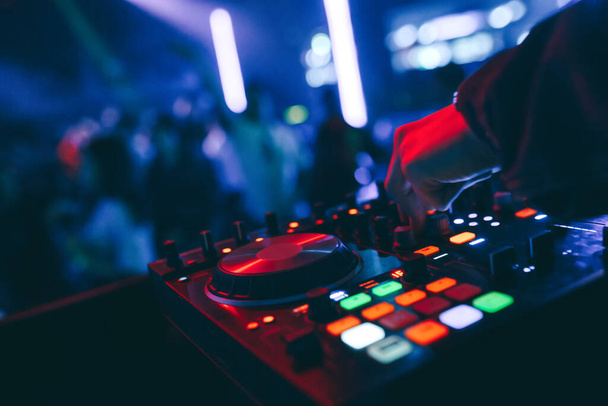 producer DJ mixer in een nachtclub met gloeiende speelt muzikale rave Dubstep Electronic Trance compositie met moderne midi controller apparaat in nachtclub Live.Musical productieproces voor kunstenaars. - Foto, afbeelding
