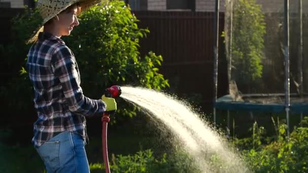 Junge Frau gießt Pflanzen in ihrem Garten mit Gartenschlauch. Hobby-Konzept - Filmmaterial, Video