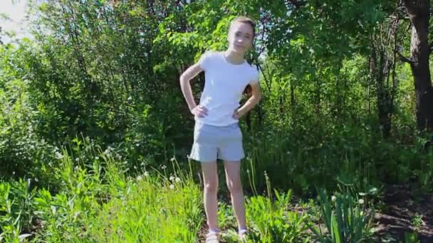 A teenage girl does gymnastics in the garden in the summer. Exercise bends to the side. 50 frames per second. - Footage, Video