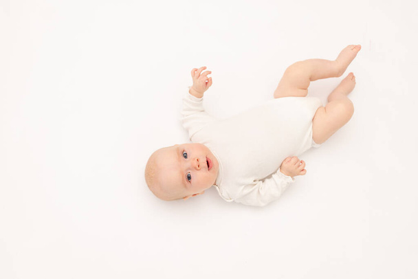linda niña en un traje de cuerpo blanco sobre un fondo blanco aislado mirando a la cámara, bebé de 3 meses de edad acostado en la cama, espacio para el texto
 - Foto, imagen