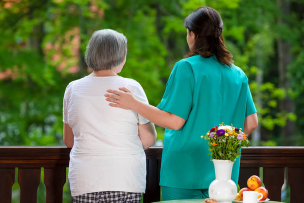 Starsza kobieta spędza czas z pomocą w domu opieki pielęgniarskiej. - Zdjęcie, obraz