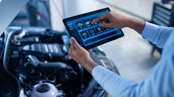 Car Service Manager or Mechanic Uses a Tablet Computer with a Futuristic Interactive Diagnostics Software. Specialist Inspecting the Vehicle in Order to Find Broken Components In the Engine Bay. - Фото, зображення