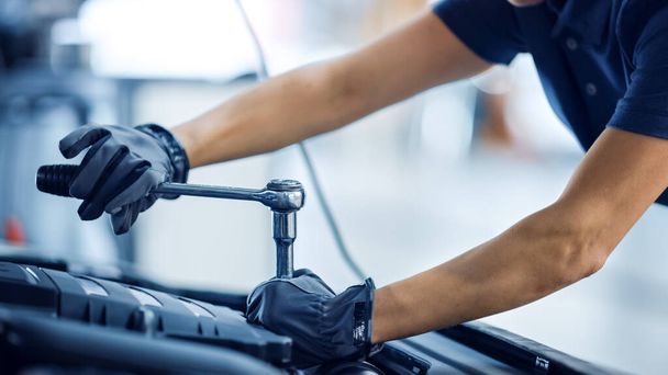 Close Up Shot of a Female Mechanic Working on a Vehicle in a Car Service. Empowering Woman Fixing the Engine. Shes Using a Ratchet. Modern Clean Workshop. - Photo, image