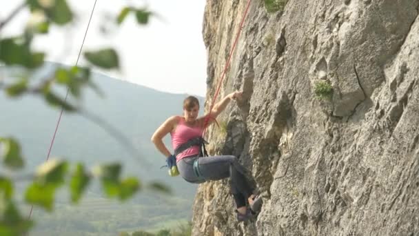 Mahtava laukaus aktiivisesta naisesta, kun hän kiipeää massiiviselle kalliolle.. - Materiaali, video