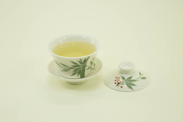 Kínai zöld tea. Tej Oolong Tea. Zöld tea egy gyönyörű hagyományos keleti csésze csészealj. Fehér alapon elszigetelve. - Fotó, kép