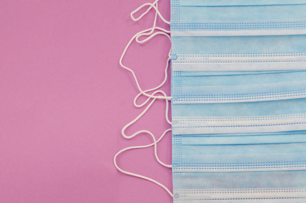Row of disposable surgical face masks to cover the mouth and nose and prevent coronavirus. Isolated on pink background. Healthcare or medical or coronavirus concept - Photo, Image