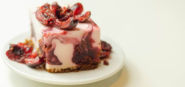 Tarta de queso japonesa con salsa de cereza y cerezas frescas en el plato de cerámica y fondo rojo, postre dulce - Foto, imagen
