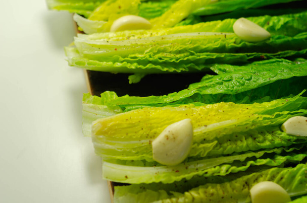 Fresh, cut romaine lettuce with garlic, pepper and salt, meal preparation - Photo, Image