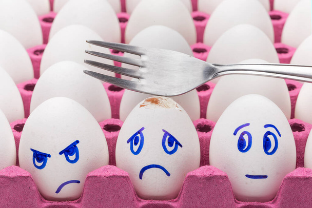 Huevos graciosos. Un huevo sonriente feliz entre la multitud triste, enojada y envidiosa de huevos aislados sobre fondo blanco
 - Foto, imagen