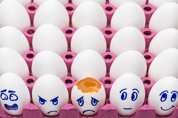 Ovos engraçados, ovos de cara em uma caixa com penas em um fundo branco fecham. Desenhos animados conceito, decoração de alimentos para crianças
 - Foto, Imagem