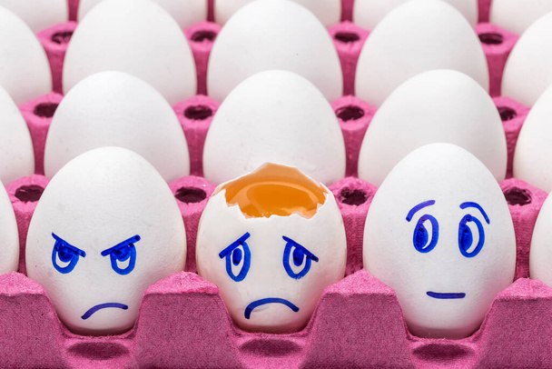 Huevos divertidos, cara huevos en un cartón con plumas sobre un fondo blanco de cerca. Concepto de dibujos animados, decoración de alimentos para niños
 - Foto, imagen