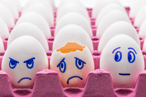 Kawaii gezicht eieren in een doos met veren op een witte achtergrond close-up. Concept cartoons, voedseldecoratie voor kinderen - Foto, afbeelding