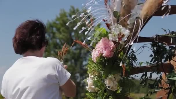 Bruiloft decorateur versiert de plaats van registratie van het huwelijk met verse bloemen. - Video