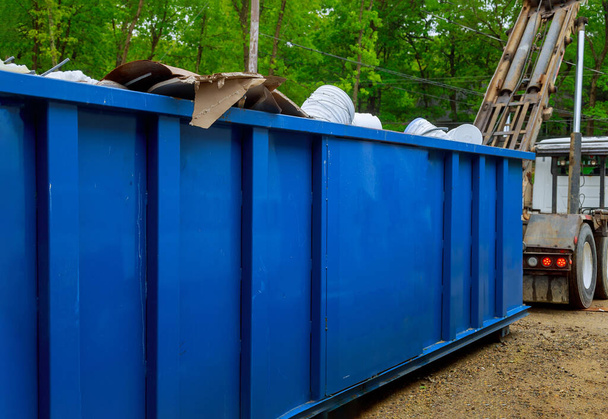 Грузовик загружает полный контейнер мусорных контейнеров будучи с мусорным контейнером
 - Фото, изображение