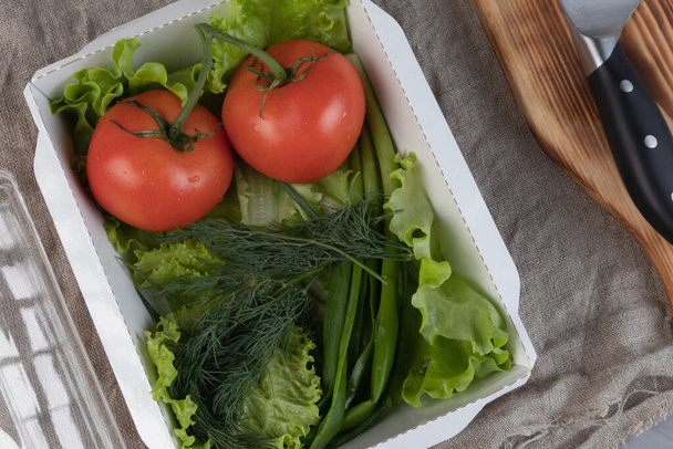 Hortalizas en el embalaje ecológico - tomates, ensalada verde fresca y eneldo en una lonchera para entrega
. - Foto, Imagen
