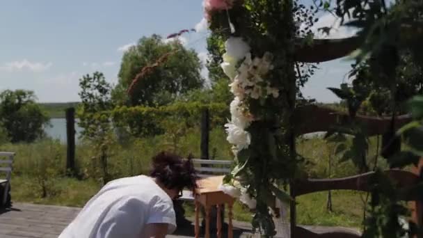 Bruiloft decorateur versiert de plaats van registratie van het huwelijk met verse bloemen. - Video