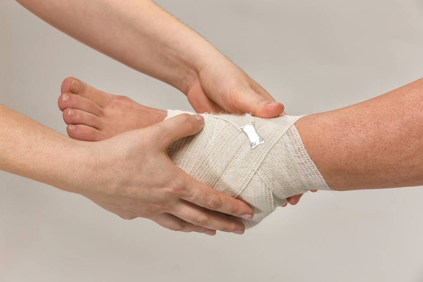 a pair of hands holding a bandage on a white background - Φωτογραφία, εικόνα