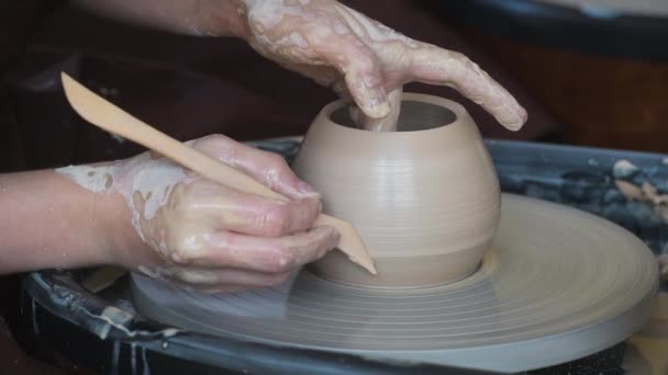 Detailní záběr nerozpoznatelného keramika tvořícího ručně vyrobenou hliněnou vázu pomocí speciálního nástroje a hrnčířského kruhu. - Záběry, video