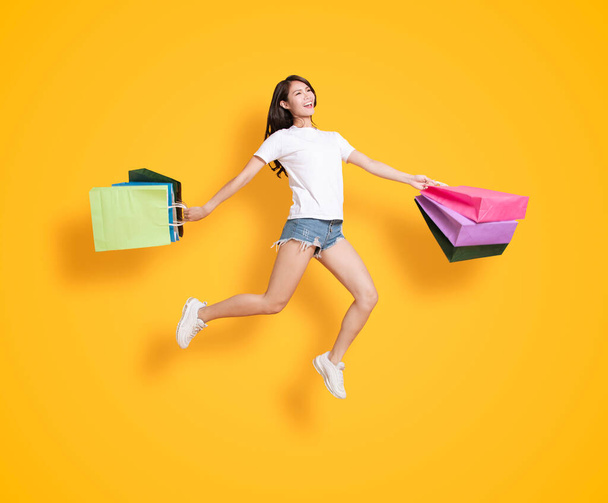 happy young woman holding with shopping bags and jumping  - Zdjęcie, obraz