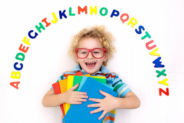 Happy preschool child learning to read and write playing with colorful roman alphabet letters. Educational abc toys and books for kids. School student doing homework. Kid reading in kindergarten. - Photo, image