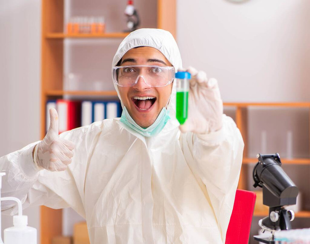 Joven bioquímico con traje protector trabajando en el laboratorio
 - Foto, Imagen