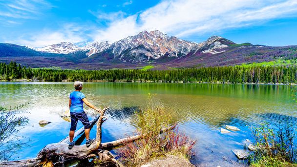 Senior woman looking at Pyramid Mountain in Pyramid Lake in Jasper National Park in Alberta, Canada. The mountains is part of the Victoria Cross Range in the Rocky Mountains - Photo, Image