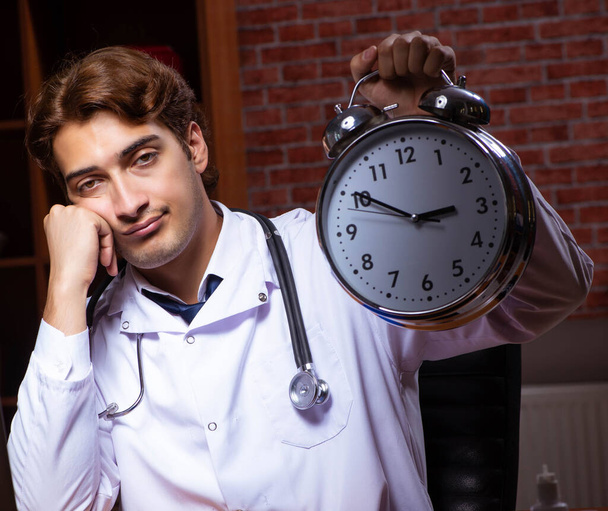 Молодой красивый врач работает в ночное время в больнице - Фото, изображение