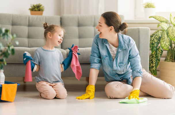 Happy family at home. Mother and daughter doing the cleaning in the house. A young woman and child girl are dusting. Cute little helper. - Foto, afbeelding