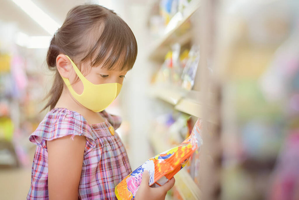 Children read labels to see the reading ingredients nutrition information and the expiration date Before buying product in the supermarket. - Foto, imagen
