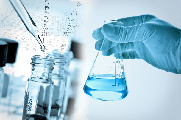 рука ученого, держащего фляжку с лабораторным стеклом на фоне химической лаборатории, концепция научных лабораторных исследований и разработок  - Фото, изображение