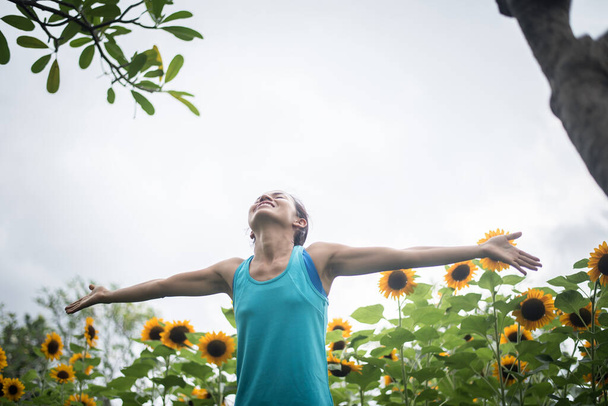 Beautiful woman with raising hands in a field of sunflowers in the summer. Women lifestyle concept. - Photo, Image