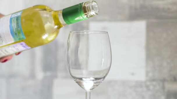 White wine is poured into glass on light background. Action. One glass of white wine in morning for single lady for breakfast. Alcoholic beverage - Video
