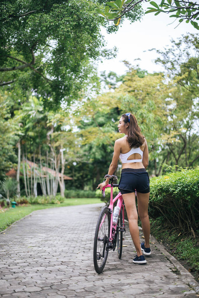 Portrait of young beautiful woman with pink bike in the park. Actractive healthy woman. - Fotoğraf, Görsel